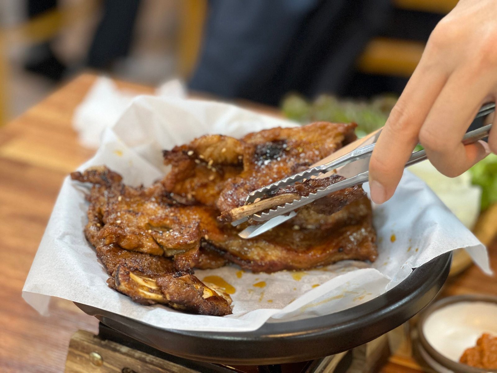 노릇하게 구워진 양념갈비를 집게로 들어 올린 모습