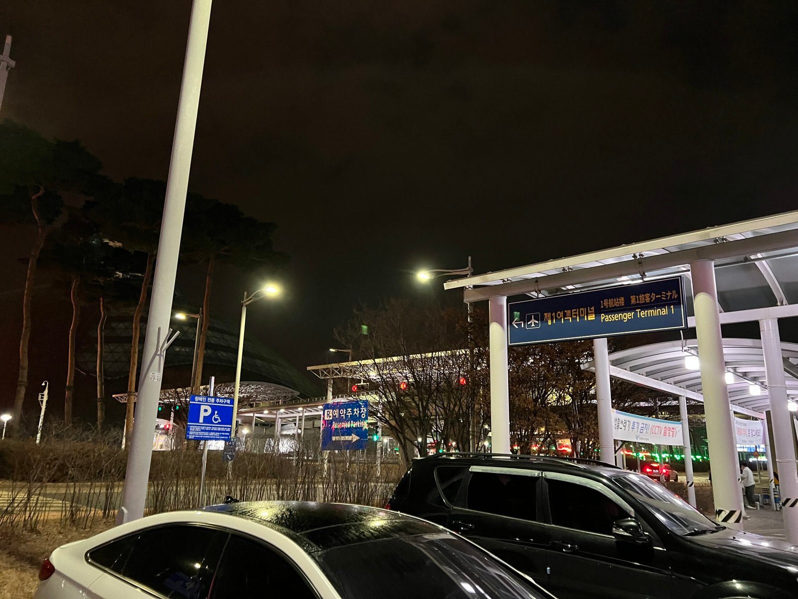 인천공항 P2 주차타워 앞 장기주차장 안내 표지와 정류장 방향