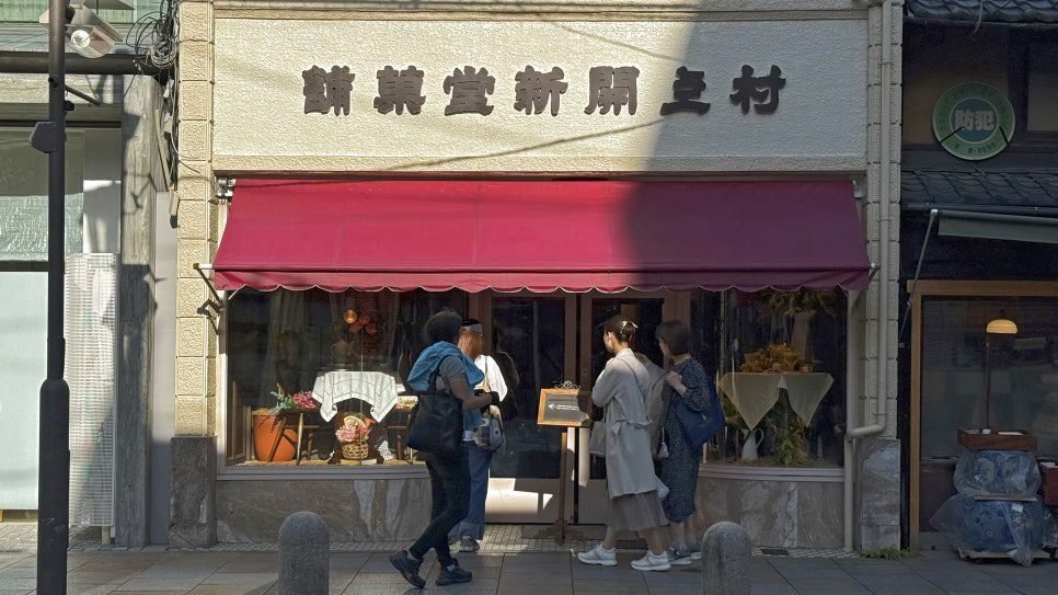 붉은 차양과 오래된 간판이 있는 교토 무라카미 가이신도 외관